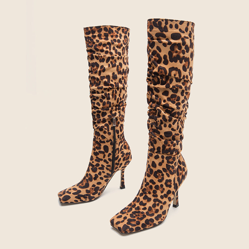 Knee-high slouchy boots in brown leopard-print faux suede, featuring square toes and stiletto heels.