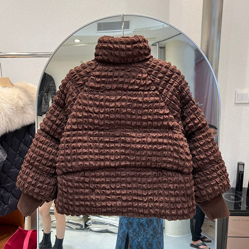 Back view of a brown puffer jacket with a stand collar and textured smocked fabric hanging on a hanger.