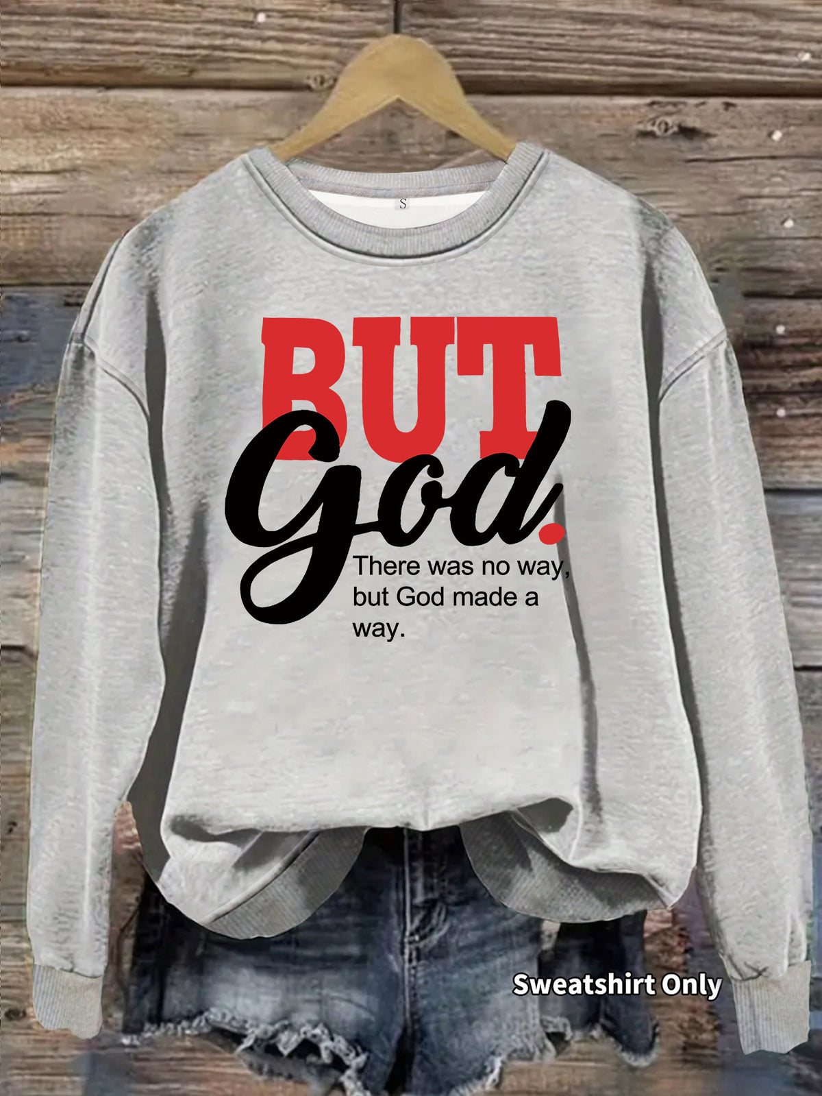 Grey cotton sweatshirt with "BUT God" graphic, crewneck, and long sleeves on a hanger.