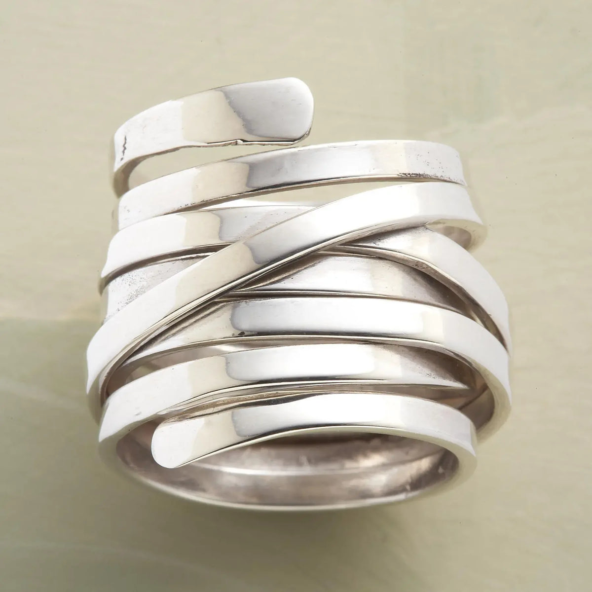 Silver-tone geometric winding hoop ring featuring modern metal jewelry design.