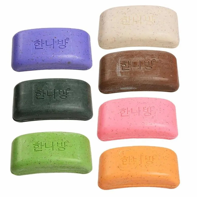 Six bars of speckled soap in purple, green, brown, pink, orange, and cream, each embossed with text.
