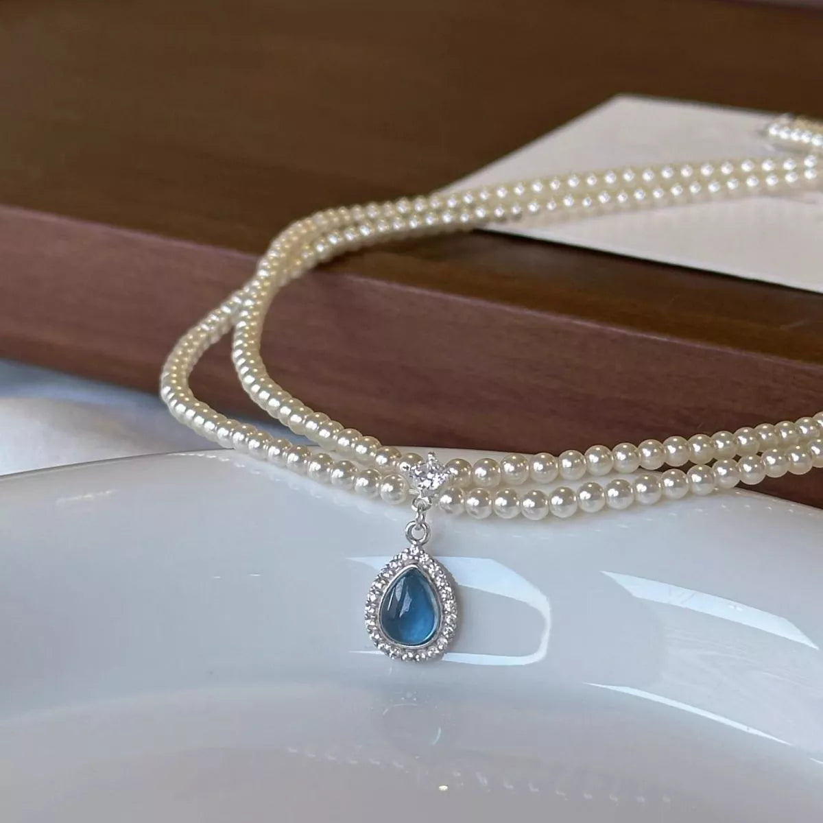 Double layered pearl necklace with teardrop pendant from Plush Fashion Hub shown on a neutral background.