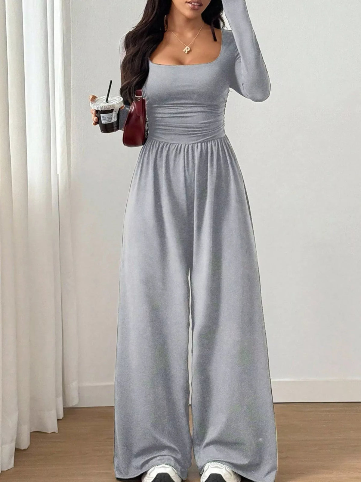 Trendsi ruched square neck wide-leg jumpsuit displayed on a hanger, featuring a fitted bodice and flowing wide-leg pants.