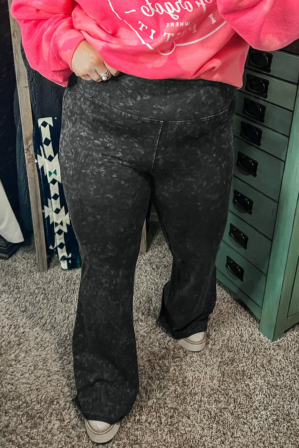 Gray high-waist flare pants with an acid wash pattern worn with a pink sweatshirt.