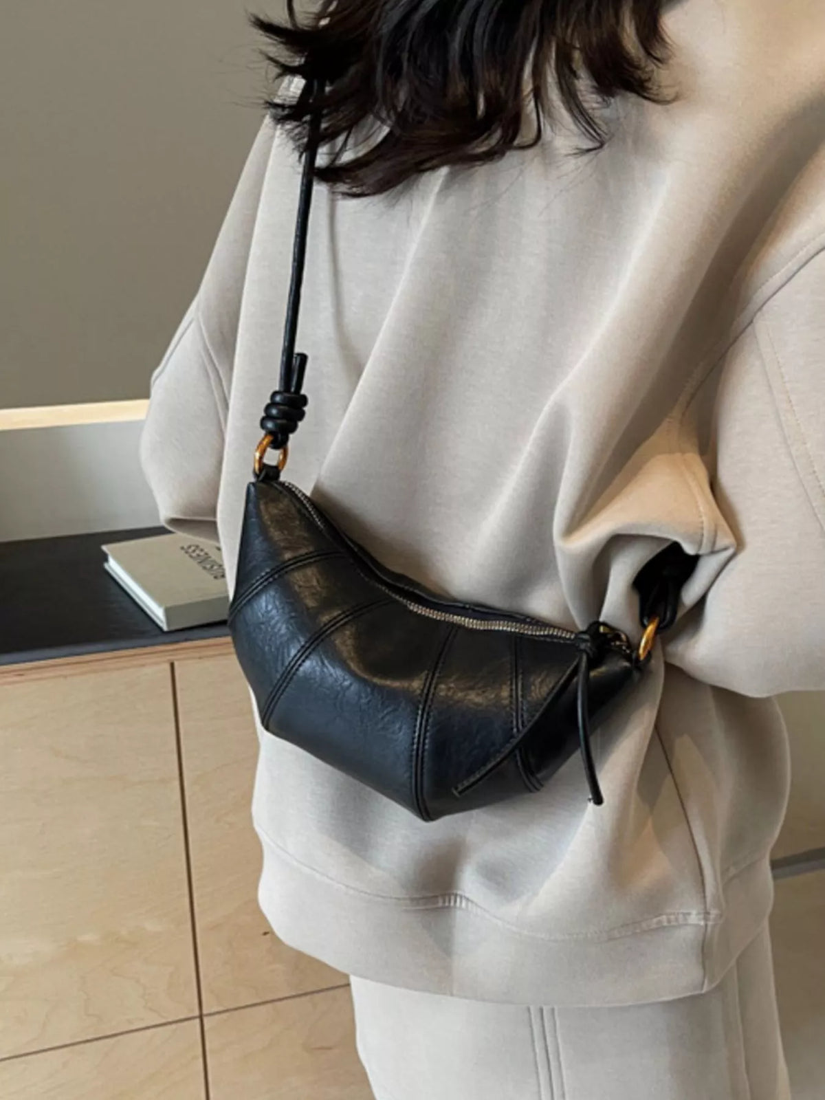 Plush Fashion Hub croissant-shaped plush crossbody bag with a soft, textured surface and adjustable strap.