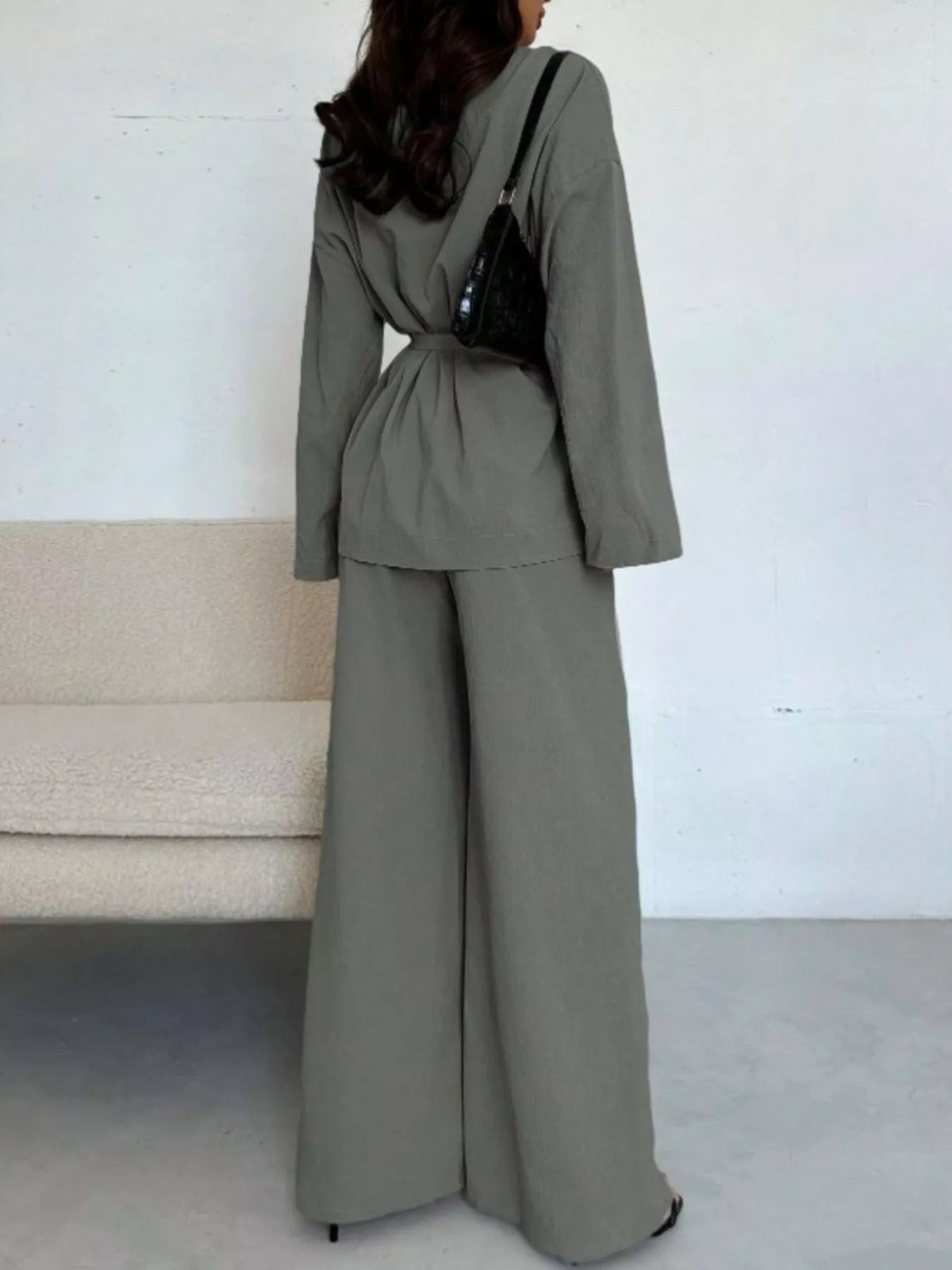 Textured woman’s tie waist top and wide-leg pants set by Trendsi, featuring a stylish, comfortable matching clothing ensemble.